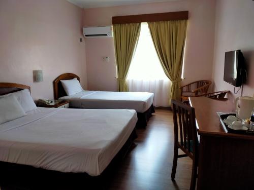 a hotel room with two beds and a desk at Hotel Seri Malaysia Bagan Lalang in Sepang