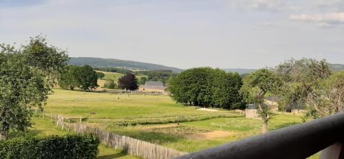 a pasture with a fence and animals in a field at B&B Domaine du Vieux Chêne in Stoumont