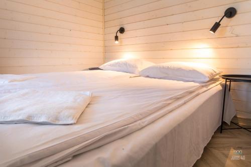 a large bed with white sheets and pillows at Jūros 40 in Šventoji