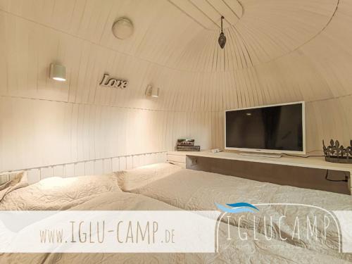 a bedroom with a bed with a large tv on the wall at Campingoase Eider in Hennstedt