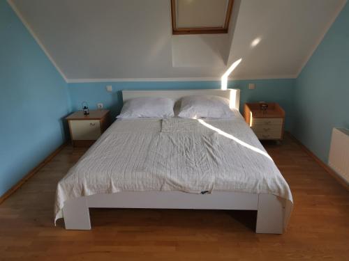 a bedroom with a white bed with two night stands at Vetrovi šumijo I in Kapele