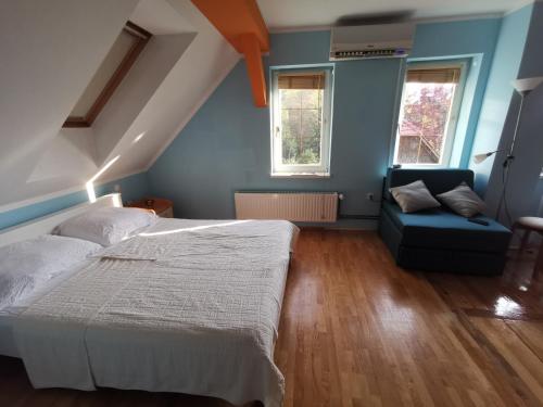 a bedroom with a bed and a couch and two windows at Vetrovi šumijo I in Kapele