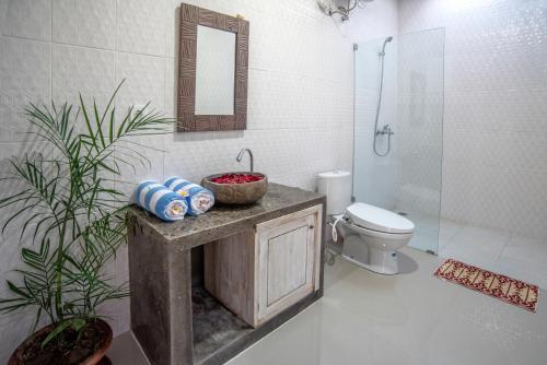 a bathroom with a sink and a toilet and a mirror at Private Room Kayu Bunga in Canggu