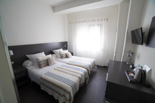 a hotel room with two beds and a window at Hostal Cabo Mayor in Santander