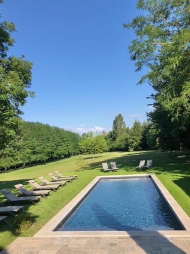 - une piscine avec des chaises longues et des chaises dans la cour dans l'établissement La Ferme de Gringalet, à Anthon