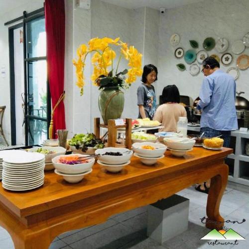 a table with bowls and plates of food on it at Lanna Oriental Hotel in Chiang Mai