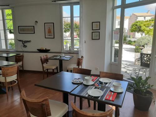 uma sala de jantar com mesas, cadeiras e janelas em Hotel Le Richelieu - Royan Atlantique em Saujon
