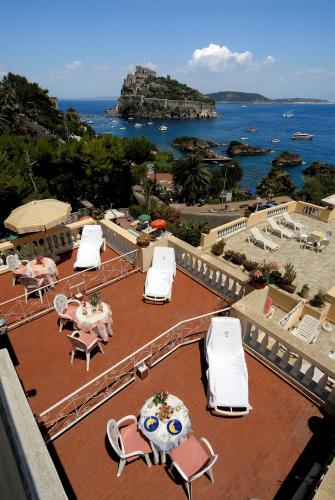 a patio with tables and chairs and the ocean at Hotel Giardino Delle Ninfe E La Fenice in Ischia