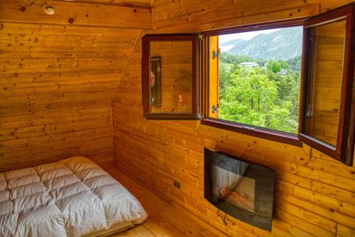 a bedroom with a bed and a window in a log cabin at Le chalet de Magali in Briançonnet