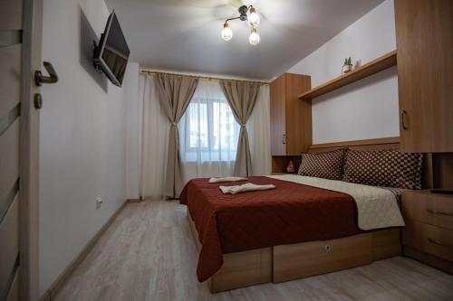 um quarto com uma cama com um cobertor vermelho e uma janela em Apartament Natalia em Tîrgu Ocna