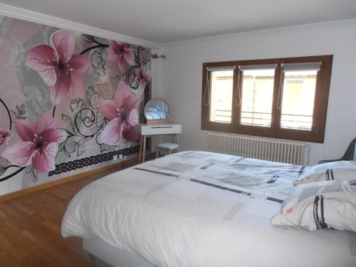 sypialnia z białym łóżkiem z kwiatami na ścianie w obiekcie Gîte des Corneilles w mieście Maubert-Fontaine