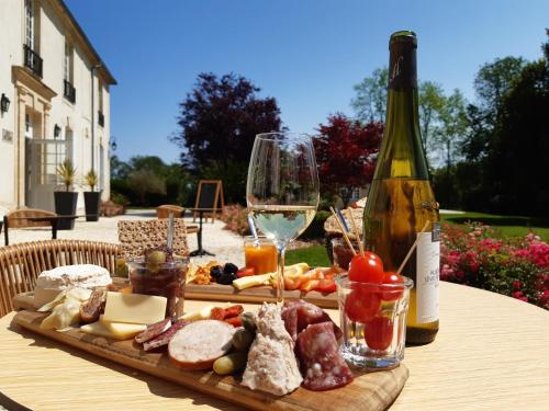a table with a bottle of wine and a plate of food at Château Saint Gilles - Bayeux in Guéron