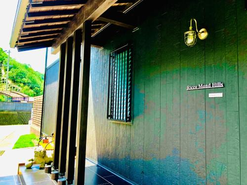 a green building with a sign on the side of it at Ricco Mond Hills Apartment Houseアパートタイプの宿は宿泊者と接しない 安全な宿 in Nachikatsuura