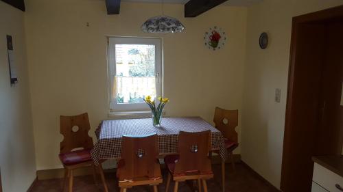 a dining room table with chairs and a vase of flowers on it at Ferienwohnung Mehlberg in Großlöbichau