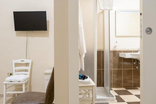 a bathroom with a tv and a chair and a sink at B&B Santi Medici in Bitonto