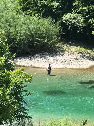 a person sitting on a bench next to a river at Boutique rooms Pri Rogovilcu in Solčava