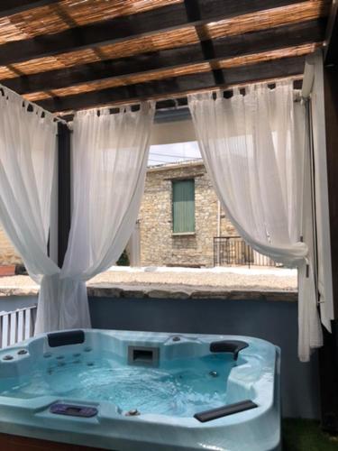 a hot tub on a balcony with curtains at RedBlue Door Two Traditional Listed Houses in Pano Lefkara