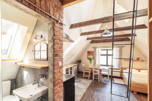 an attic bathroom with a sink and a bedroom at Apartament Gdański Gród in Gdańsk