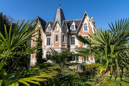 a large house with palm trees in front of it at Le Château des Forges in Angers