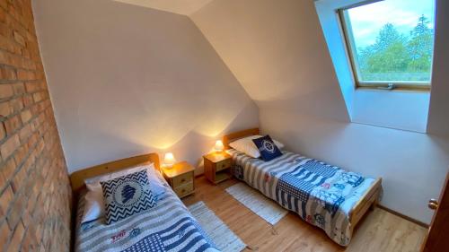 a attic room with two beds and a window at Dom murowany Siedlisko in Sarbinowo