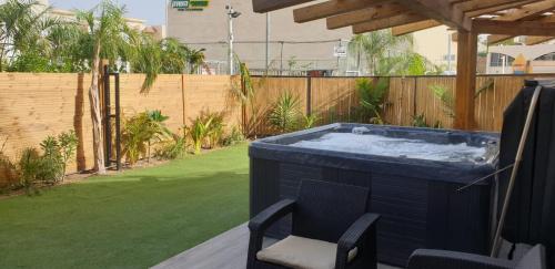 einen Whirlpool im Garten mit einem Stuhl in der Unterkunft Avshalom Holiday Apartments in Eilat