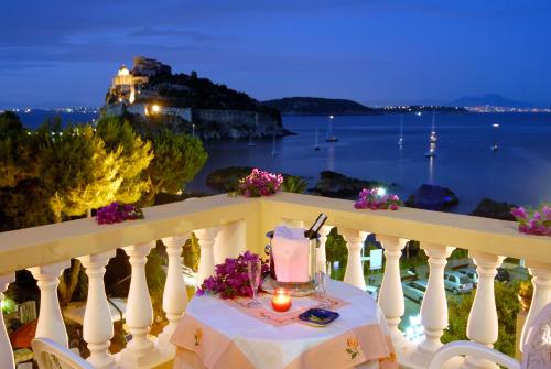 a table on a balcony with a view of the ocean at Hotel Giardino Delle Ninfe E La Fenice in Ischia