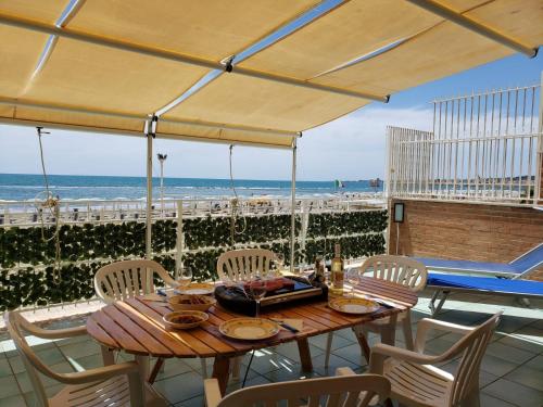 a table and chairs on a patio with the beach at Incantevole casa sul mare vicino a Roma in Nettuno