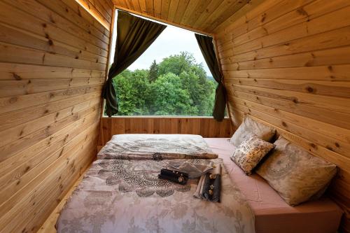 Cama en habitación de madera con ventana en Glamping Health Resort, en Kamnik