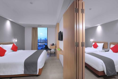 En eller flere senge i et værelse på Neo Hotel Puri Indah