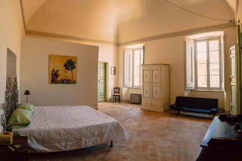 um quarto com uma cama, um sofá e janelas em Appartamenti Sole alle Torri em Assis