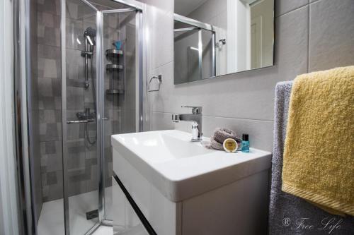 een witte badkamer met een wastafel en een douche bij Mgarr Waterfront Cosy Apartment 3 by Ghajnsielem Gozo in Mġarr