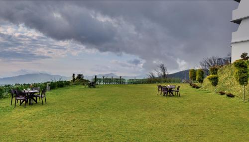 a group of tables and chairs on a grass field at Ekant Retreat Resort in Chail