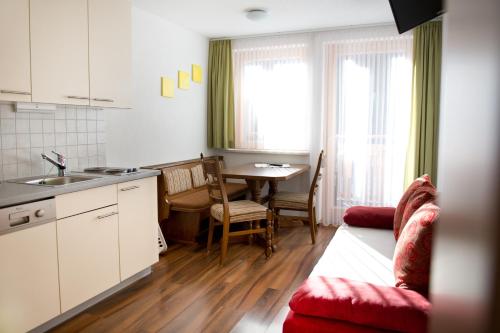 a kitchen and living room with a red couch and a table at Hotel Garni Ragaz in Damuls