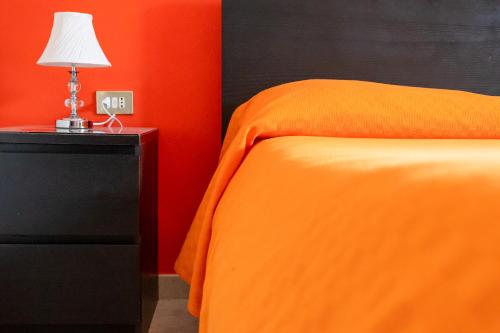 a bedroom with an orange bed and a lamp on a nightstand at B&B Santi Medici in Bitonto