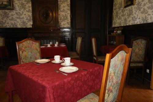 a table with a red table cloth and plates on it at Domaine de Champ rose in Saint-Laurent-de-Belzagot