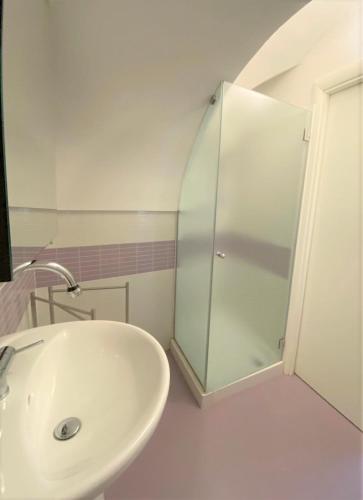 uma casa de banho com um lavatório e uma cabina de duche em vidro. em La casetta em Noci