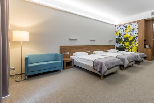 Pokój z 2 łóżkami i niebieskim krzesłem w obiekcie Kolumna Park Hotel w mieście Dobroń