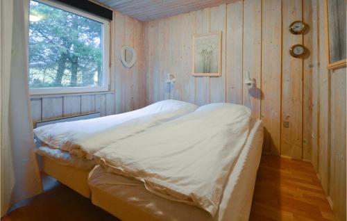 a bed in a wooden room with a window at 3 Bedroom Lovely Home In Spttrup in Spottrup