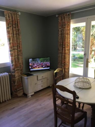 - un salon avec une table et une télévision sur une armoire dans l'établissement Les Pierrottes pour 2, à Mornac