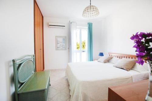 a white bedroom with two beds and a chair at Villa Irene in Torre Santa Sabina