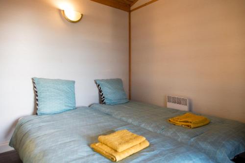 a bedroom with two beds with blue sheets and yellow towels at LES CHALETS D HERMINE in Montredon-Labessonnié