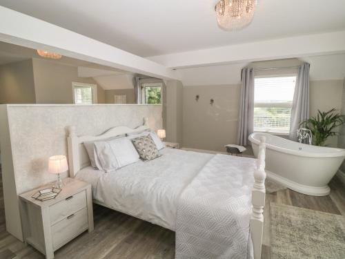 a bedroom with a white bed and a bath tub at The Wren in Colwyn Bay