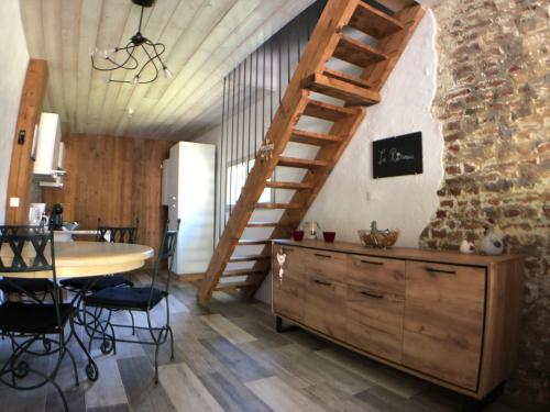 Habitación con escalera de madera, mesa y sillas en la Roseraie, en Chooz