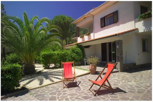 two red chairs sitting in front of a house at Appartamenti Tallinucci in Lacona