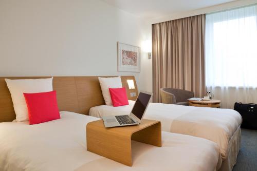 um quarto de hotel com duas camas com um computador portátil numa mesa em Novotel Constantine em Constantina