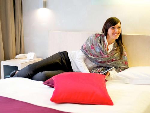 a woman sitting on top of a bed at Mercure Palermo Centro in Palermo