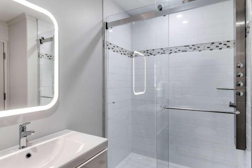 a white bathroom with a shower and a sink at Quality Inn & Suites Garden of the Gulf in Summerside