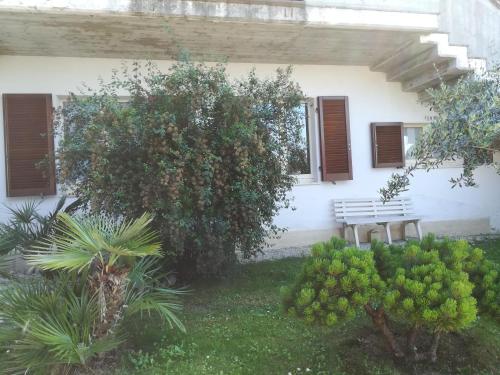 a white house with a bench in the yard at Angolo Felice B&B in Castignano