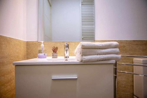 W łazience znajduje się umywalka, lustro i ręczniki. w obiekcie Apartamento en el corazón de Madrid Netflix w Madrycie