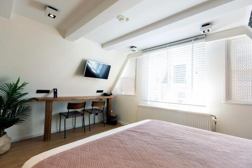 Schlafzimmer mit einem Bett, einem Schreibtisch und einem Fenster in der Unterkunft Quentin Golden Bear Hotel in Amsterdam